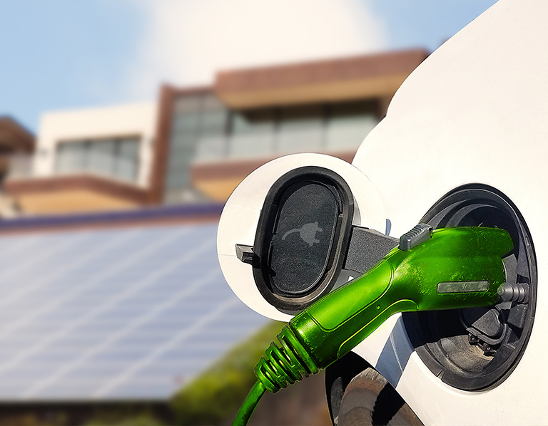 Photo of electric vehicle charging with solar panels in the background