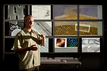 Photo of a man in front of multiple computer screens  that present different views of ultra structures of pretreated biomass materials in NRELs Cellular 