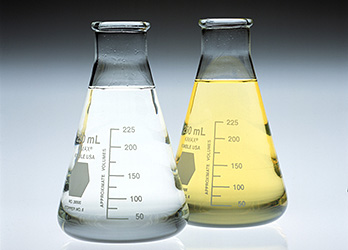 Photo of two Erlenmeyer flasks showing a comparison between a clean Fischer-Tropsch diesel fuel (left flask with clear liquid) and conventional No. 2 diesel fuel (right flask with pale yellow liquid).