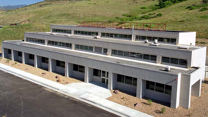 Photo of the front of the Thermal Test Facility, a white building on the NREL campus, on a sunny day.