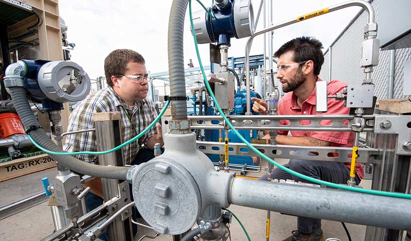 Photo of two researchers working on equipment at the hydrogen storage pad at the Energy Systems Integration Facility.