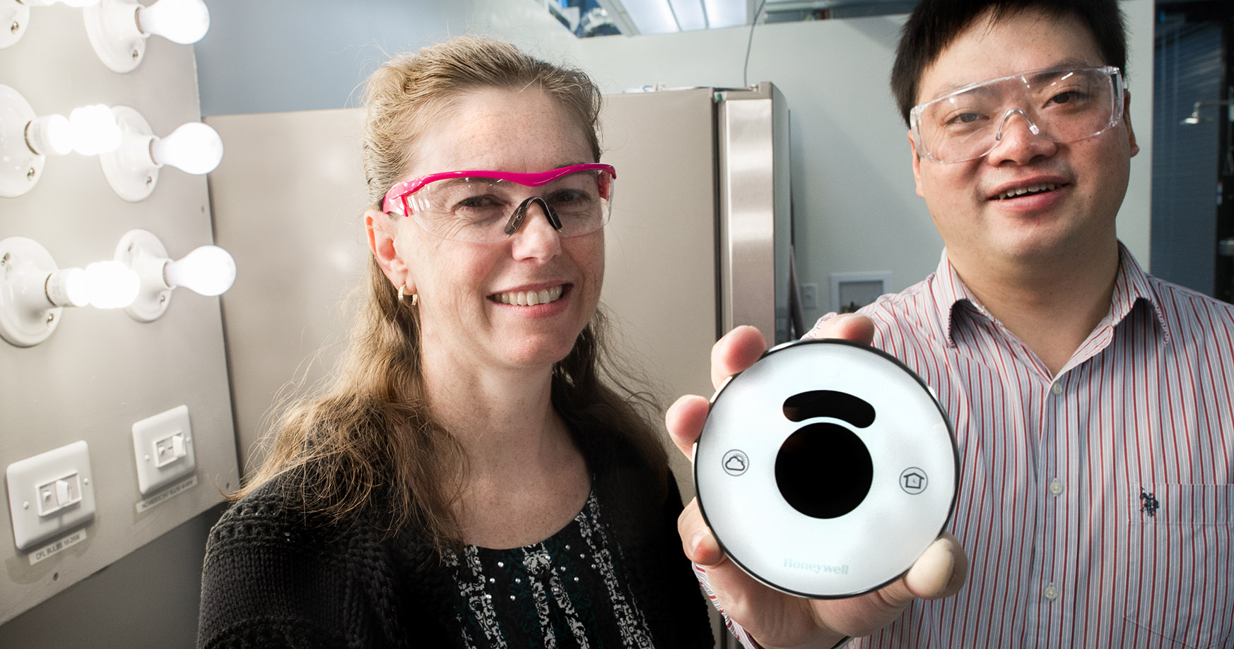 Photo of a pair of NREL researchers who received a record of invention for a home energy management system in a smart home laboratory.