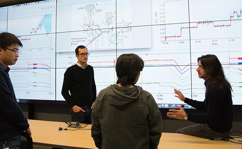 Photo of a group of researchers reviewing the results of numerical simulations in a test of real-time distributed optimization algorithms.