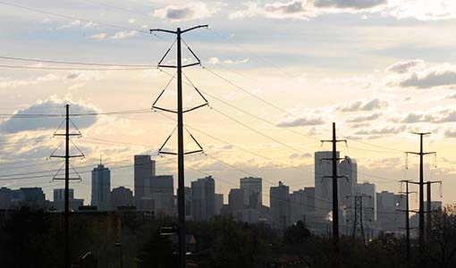 Photo of power lines with the Denver skyline in the background.