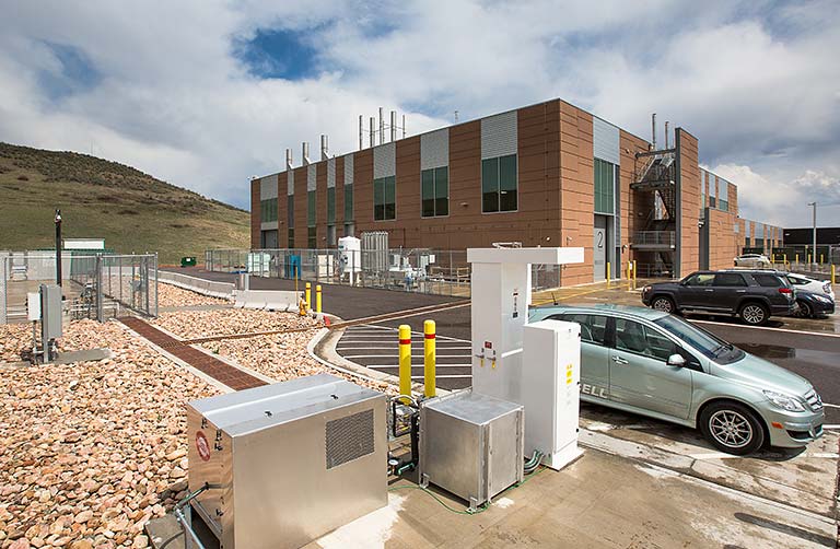 Photo of the Hydrogen Infrastructure Testing and Research Facility building, with hydrogen fueling station and fuel cell vehicles.