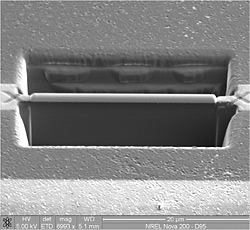 Second of three TEM images showing cutting of trenches to remove a wafer section. This is a side view, showing the depth of the rectangular trenches, with a slim bridge of material in the middle.
