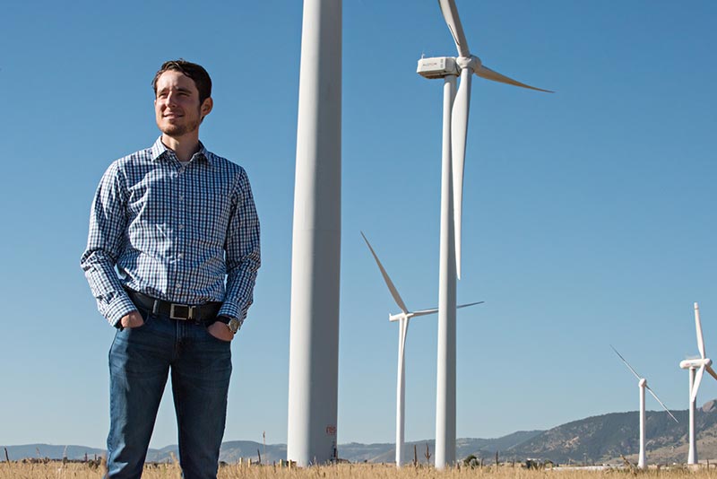 An NREL researcher stands near wind turbines at the National Wind Technology Center.