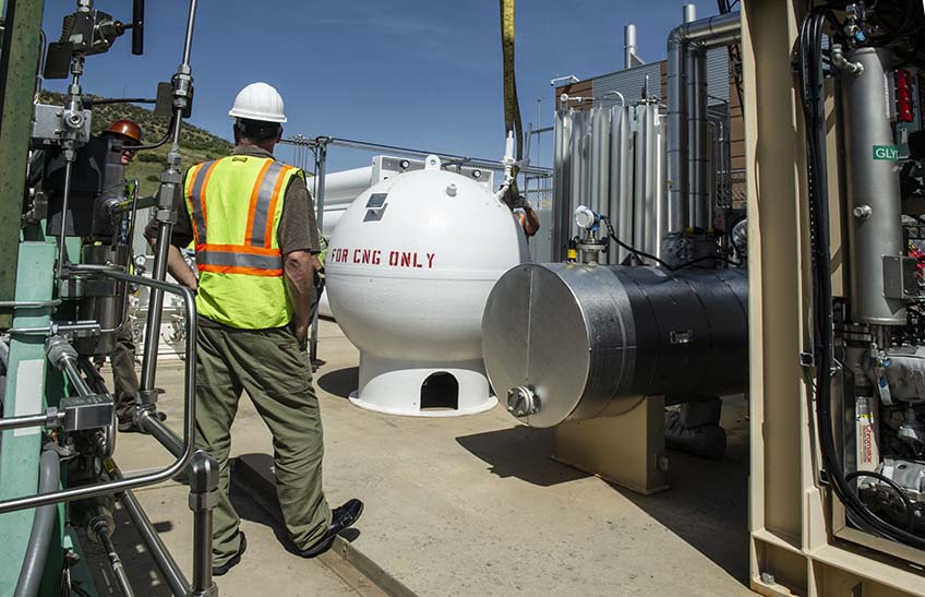 Crews install a large round storage vessel for natural gas.