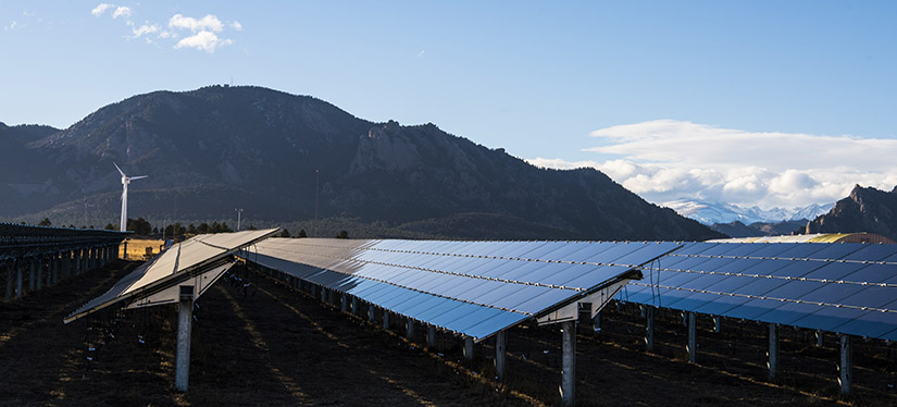 Photo of an array of solar panels with mountains in the background