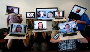 In this photo, six researchers playfully hold up laptops in front of their faces. Each laptop has a photo of the face of the person holding it.