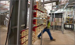 Photo of a man walking past a rack of electricity switchers.