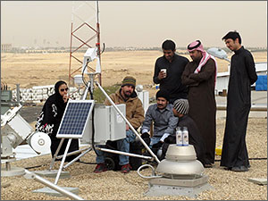 Photo of a group people standing in the desert installing a solar monitoring instrument.