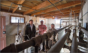 Photo of three men standing in the basement of a home. 