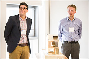 Photo of two men standing with a small-scale model home.