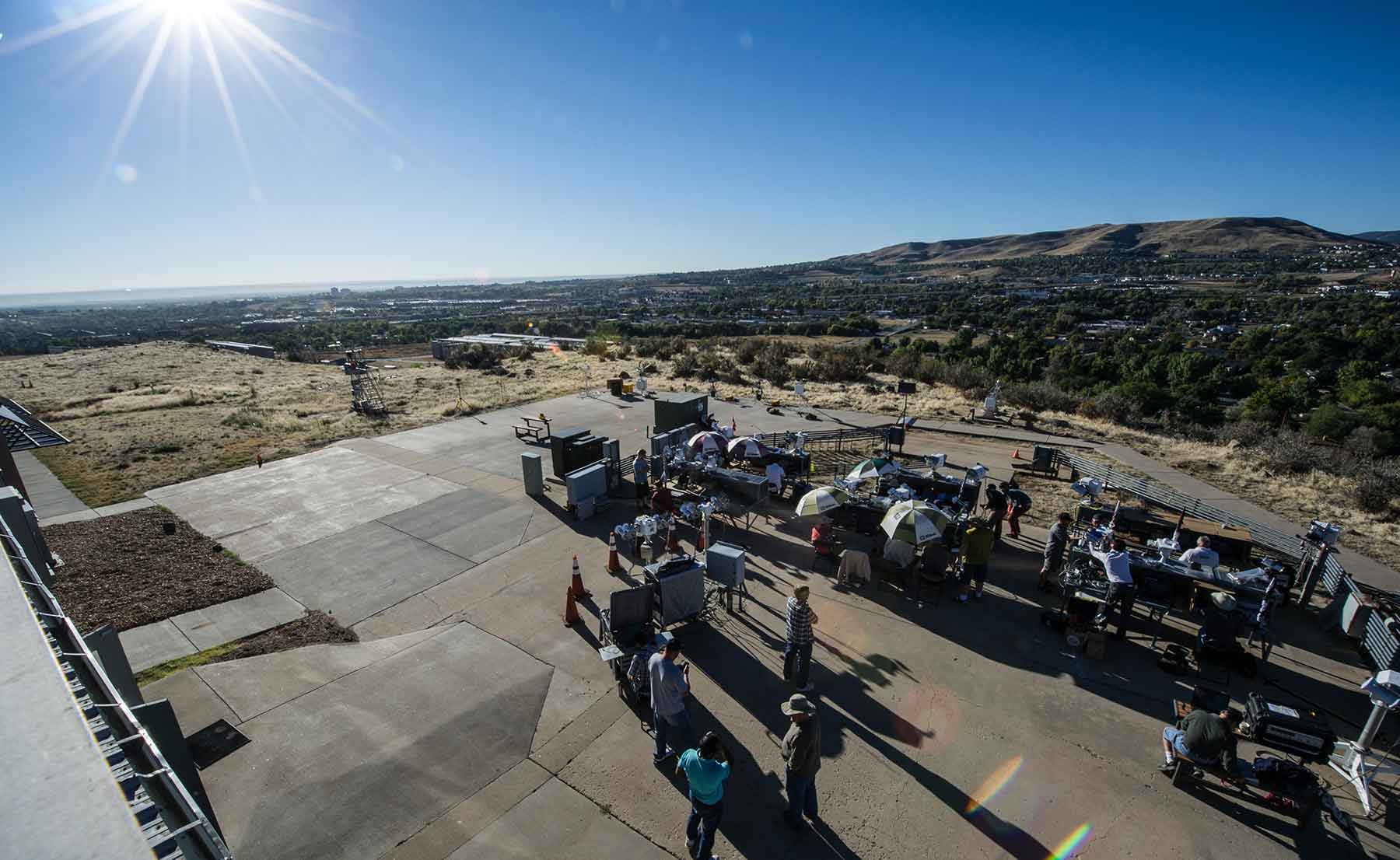 Several dozen people work outside with solar radiation instruments on a mesa.