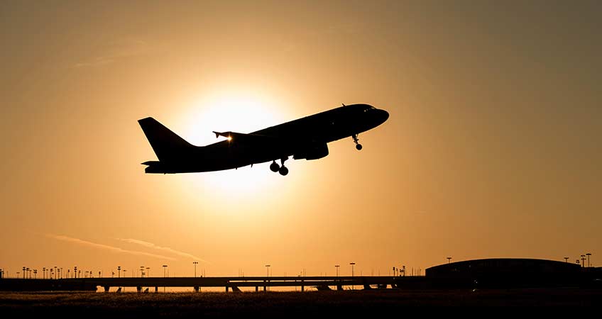 An airplane takes off at Dallas Fort Worth International Airport at sunset.