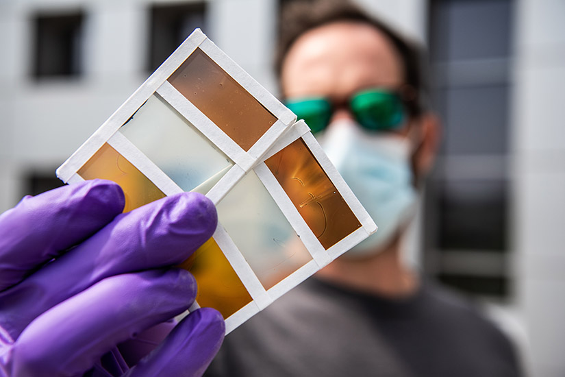 Photo of a researcher holding a sample of perovskite window technology