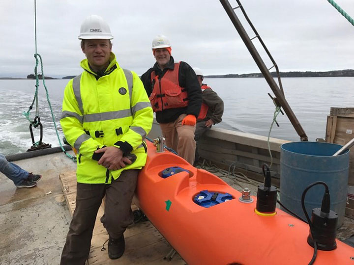 Researchers standing in front of marine energy equipment.