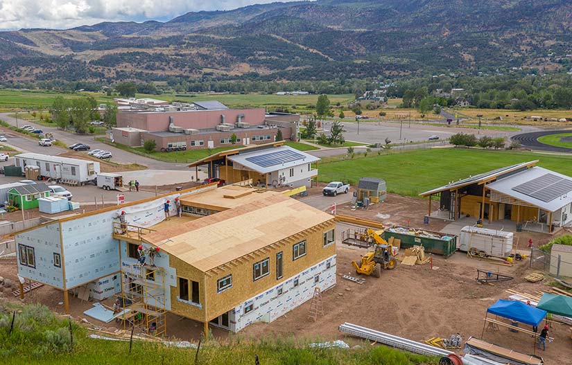 Photo of houses in a mountain neighborhood being constructed with built-in solar panels.