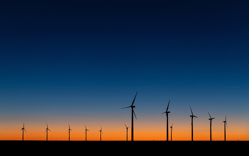 A photograph of wind turbines at sunset. 