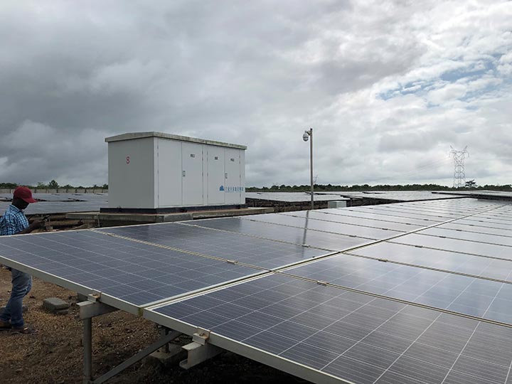 A picture showing a cloudy sky, solar panels, and a battery storage system.