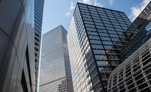 Tall, glass-covered buildings reflecting a clear blue sky.