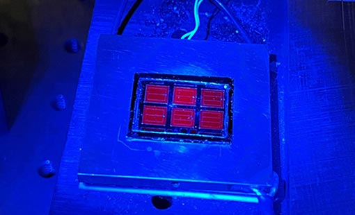 A solar cell shining red under blue luminescence.