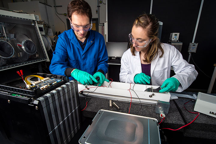Two researchers work on a relithiation reactor, a chemical bath used to replenish batteries, in NREL's Energy Systems Integration Facility, Materials Characterization Lab. 