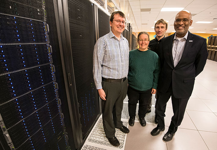 Four researchers pose in front of NREL's Eagle supercomputer.