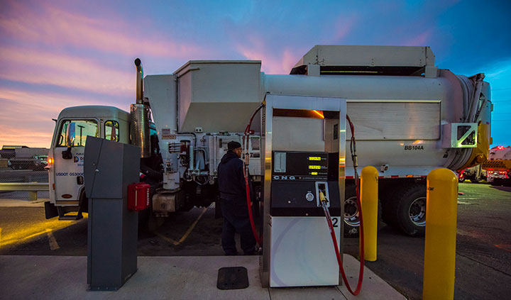 A worker at the City and County of Denver Platte Facility fuels a garbage truck with compressed natural gas.