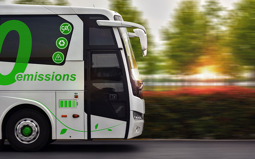 A zero-emission electric bus drives with a green background.