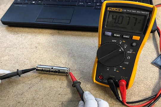 A researcher uses a tool to take a measurement from a lithium-ion battery.