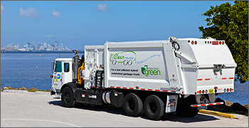 Photo of garbage truck with view of lake and city in background.