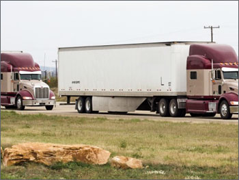 Photo of two tractor trailer trucks driving in close proximity.
