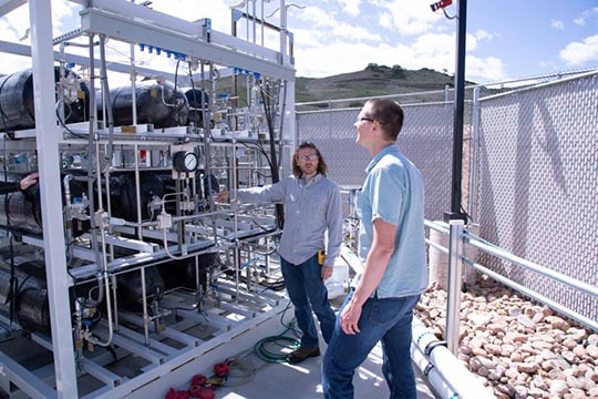 Two researchers standing outside by a new hydrogen storage and fueling research facility.
