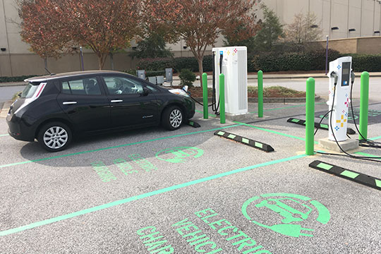 An electric vehicle charges in a parking lot.