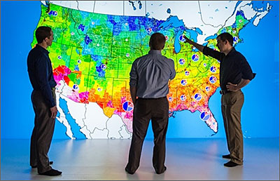 Photo of researchers looking at a large, colorful map of the United States.