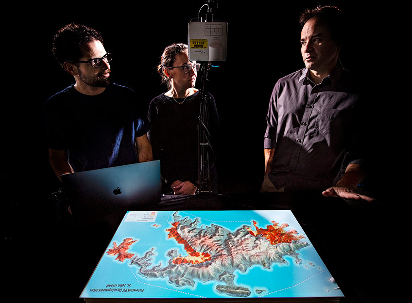 Photo of three researchers examining a topographical map.