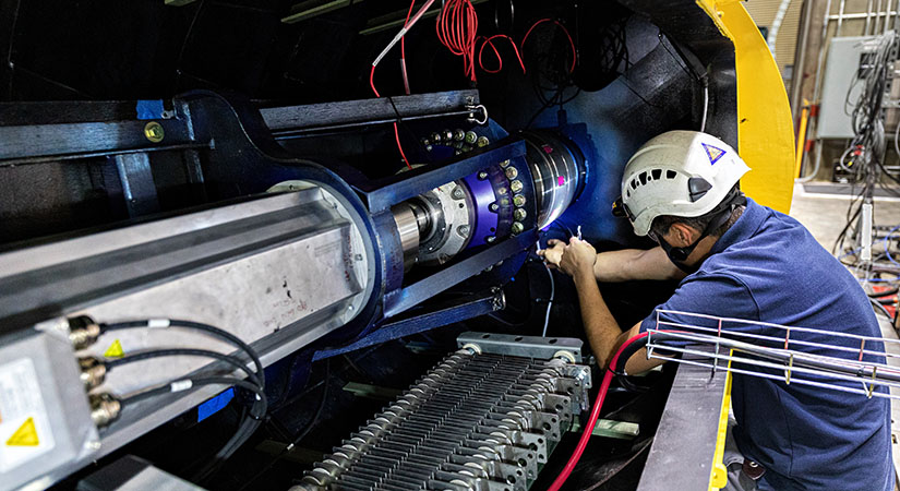 Researcher inside a large machine making adjustments