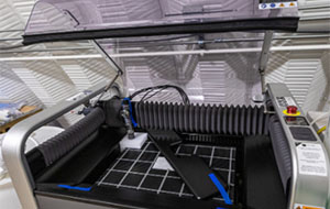 A machine with transparent lid open, revealing a gridded platform interior.