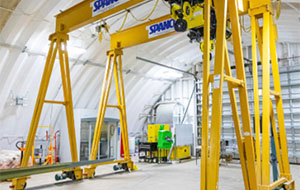 Yellow metal frames that could fit around a car span the interior of a hangar.