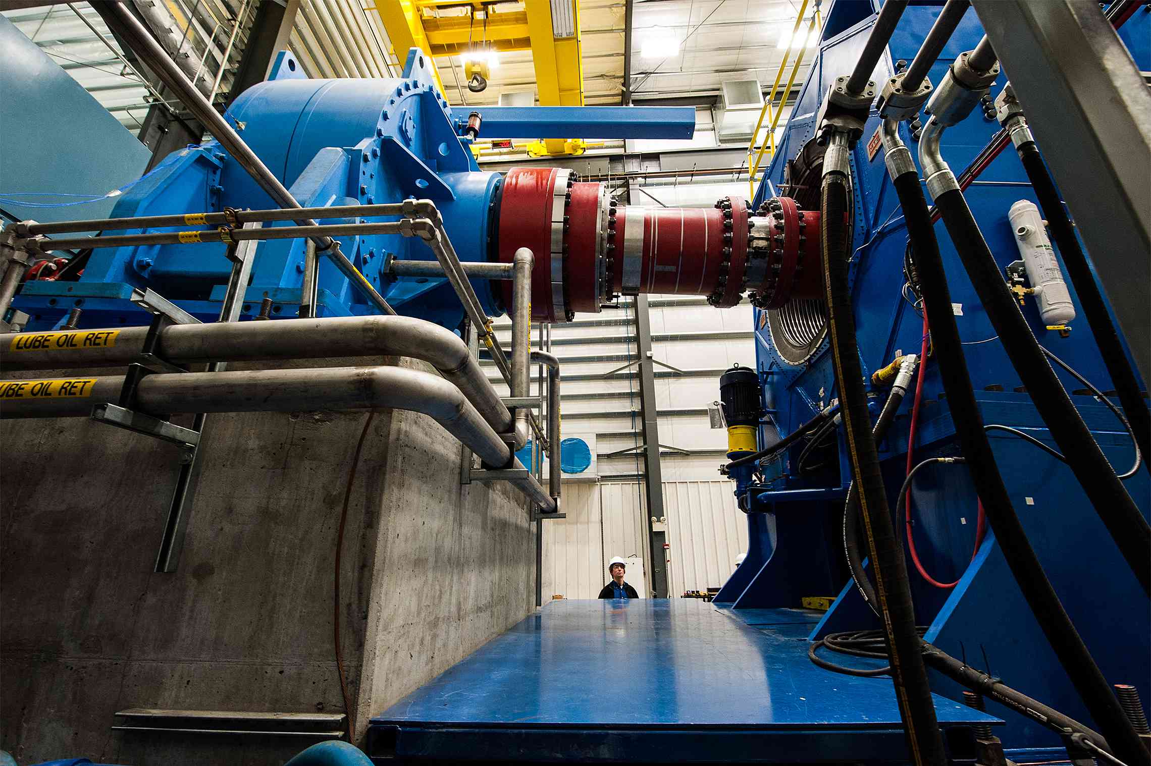 Photo of large blue and red test machinery with a man looking up at it.