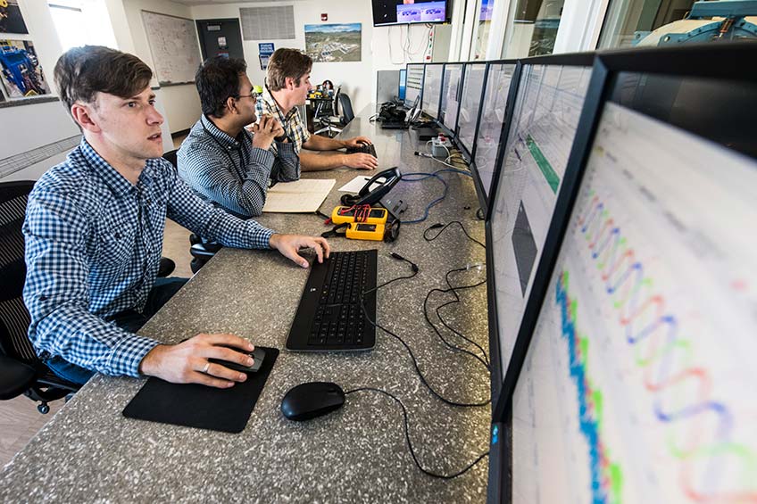 NREL researchers work on microgrid integration analysis in the CGI control room.