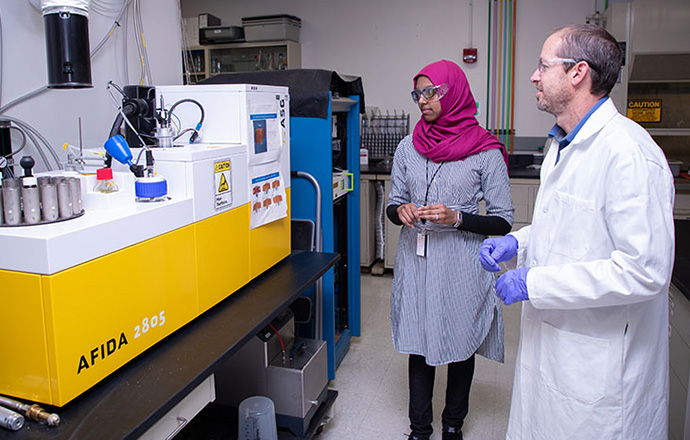 Two researchers looking at a fuel properties analysis machine.