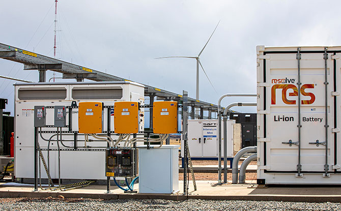 Photo of energy storage with a wind turbine in the background.