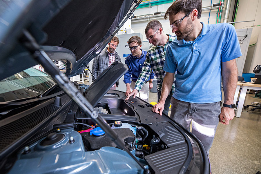 Researchers look under the hood of a vehicle.