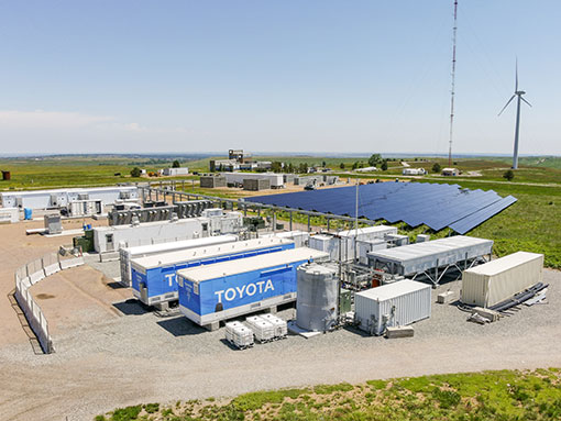 Energy storage containers outside in front of solar array and wind turbine
