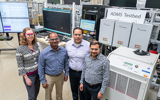 Four people stand for photo inside lab