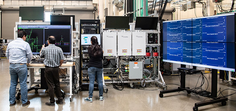 People work on large computer displays inside laboratory.