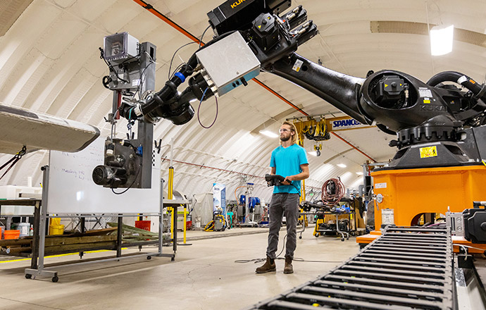 Photo of a man remotely controlling a robotic arm in a lab